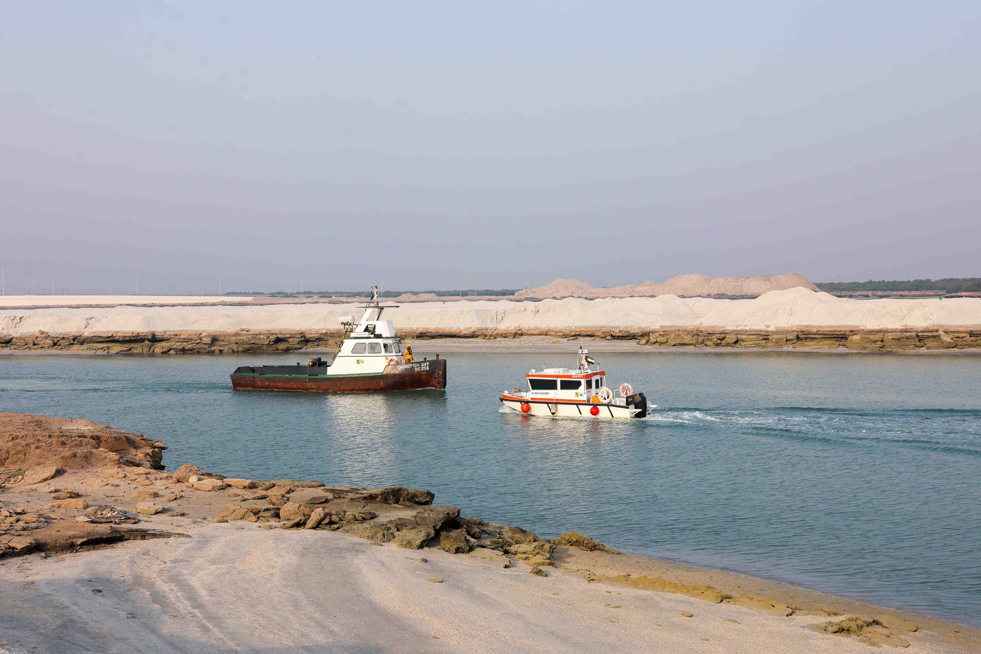 Workboat Swordfish Bay and survey launch Plancius Bay passing each other in a dredged channel.