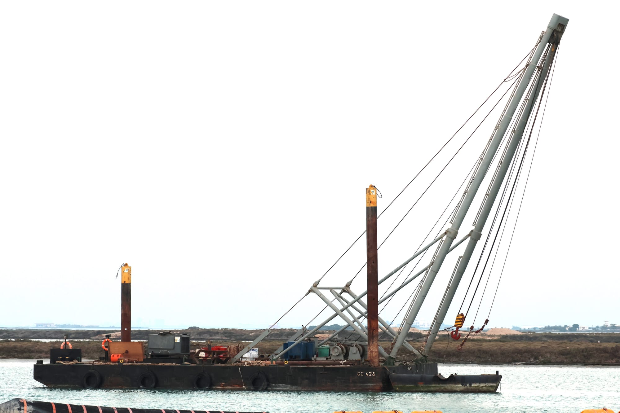 Blue tug named Shark Bay sitting in a dredged channel with sand embankments behind.