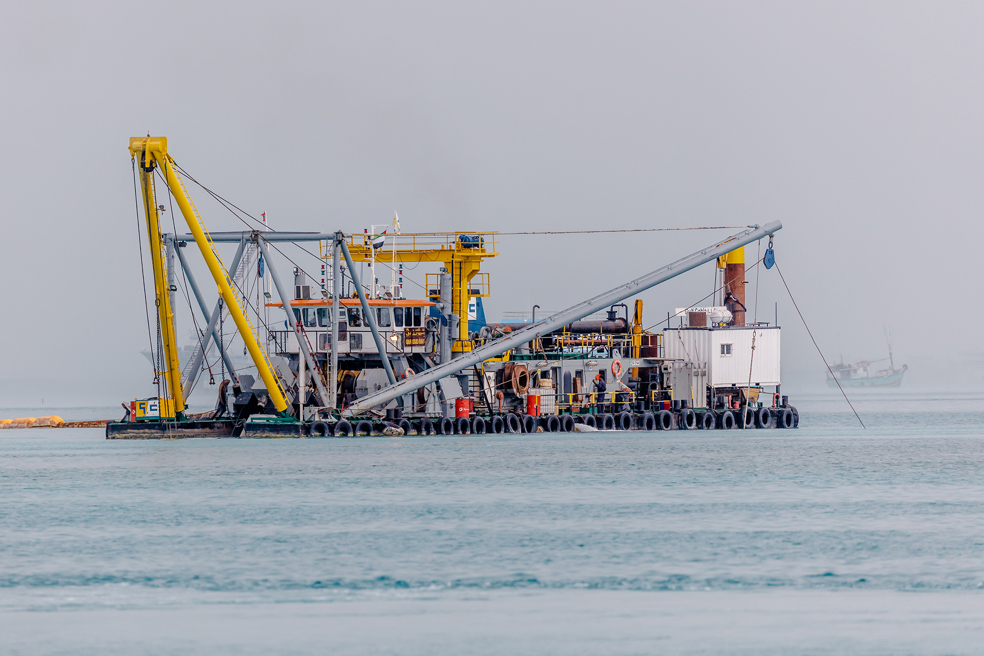 Close view down a dredger ladder to the toothed cutter head and suction pipe at the waterline.