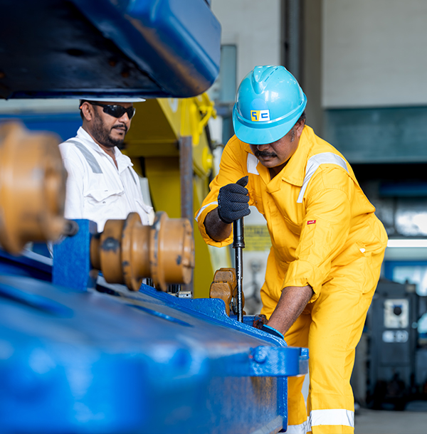 Engineer in protective gloves servicing machinery in a dredger engine room.