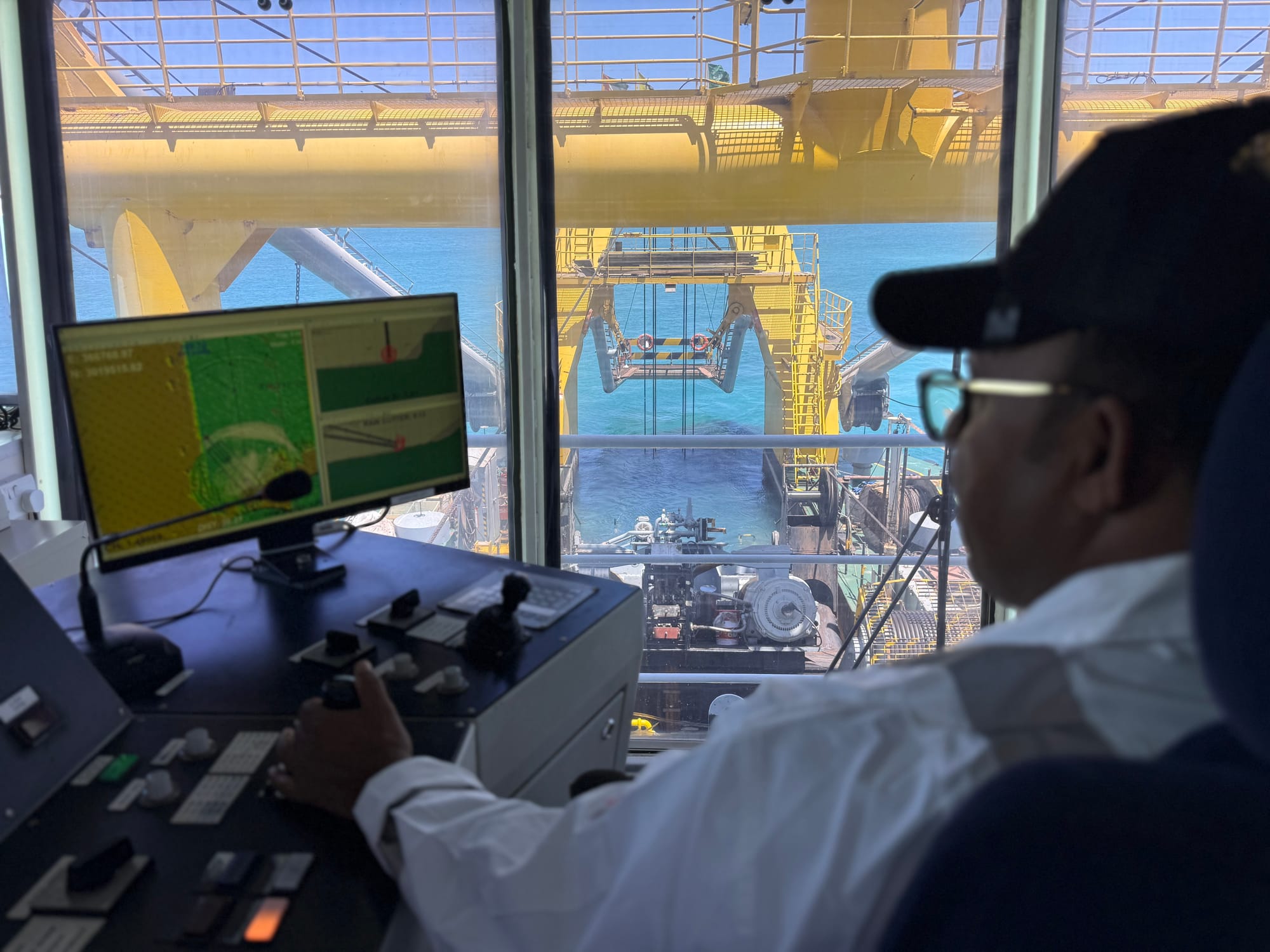 Gulf Cobla dredge operator at the controls, watching the cutter ladder through the cabin window with the survey display alongside.
