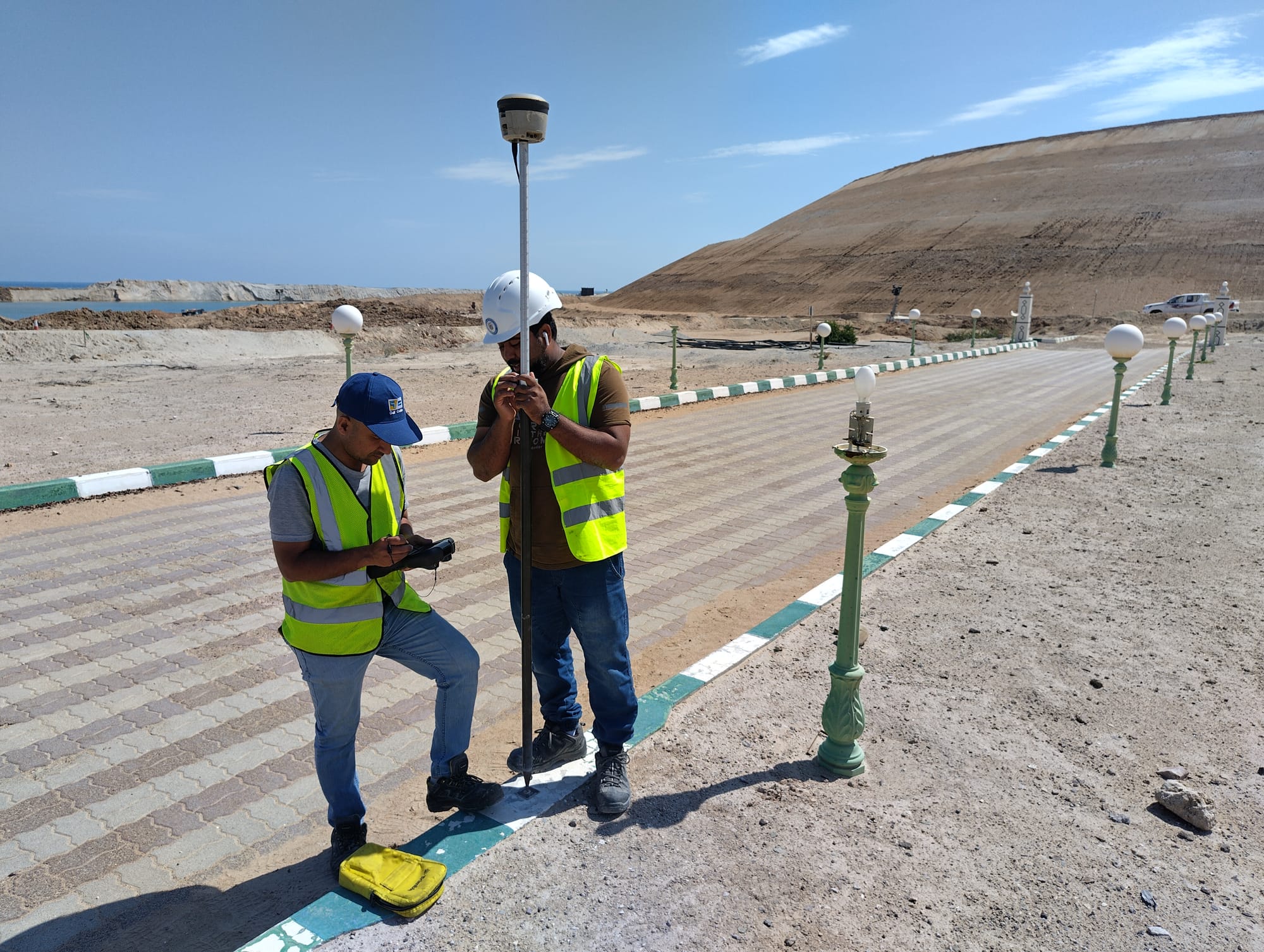 Two Gulf Cobla engineers holding a survey chart beside open water.