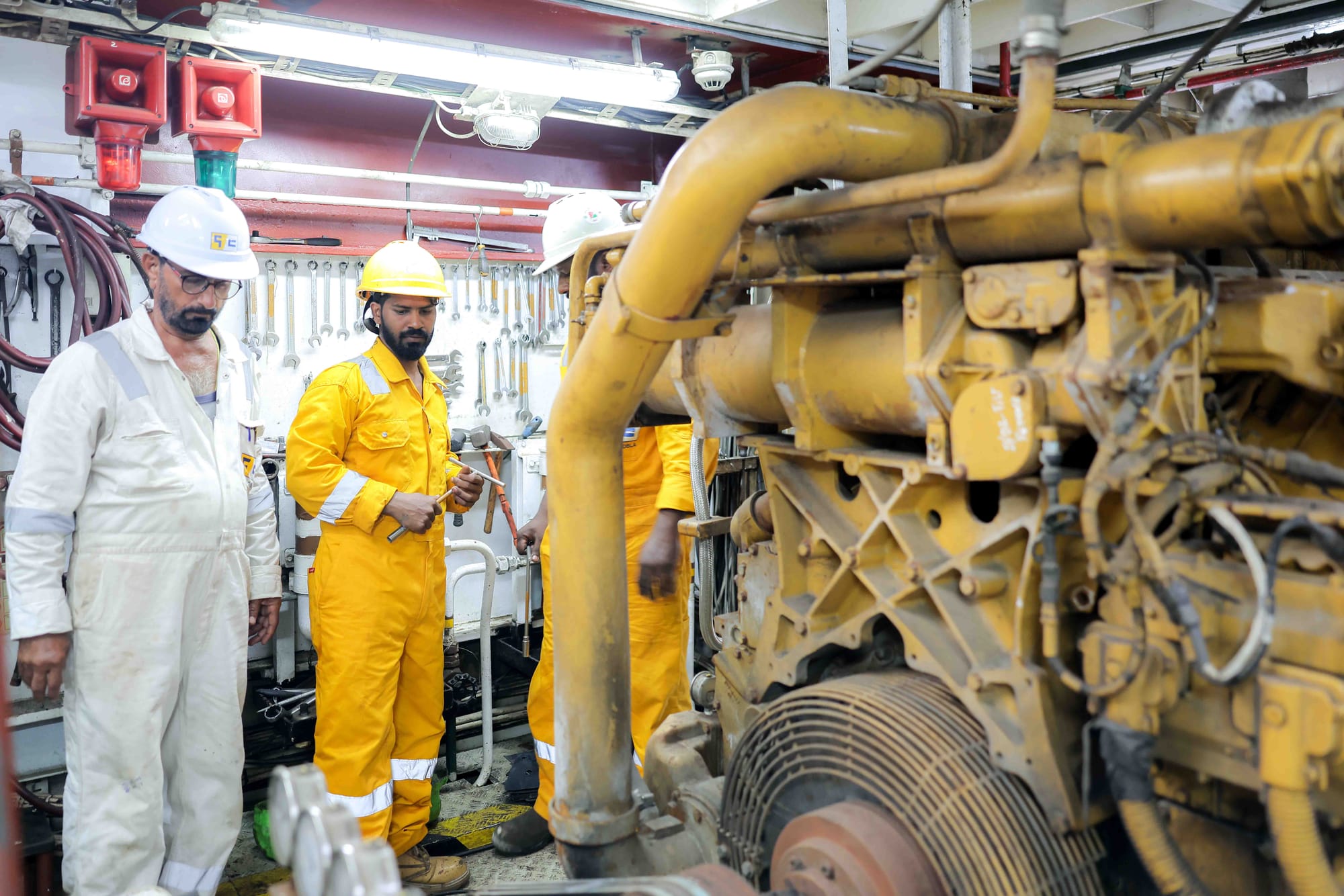 Crew inspecting an engine in the engine room.